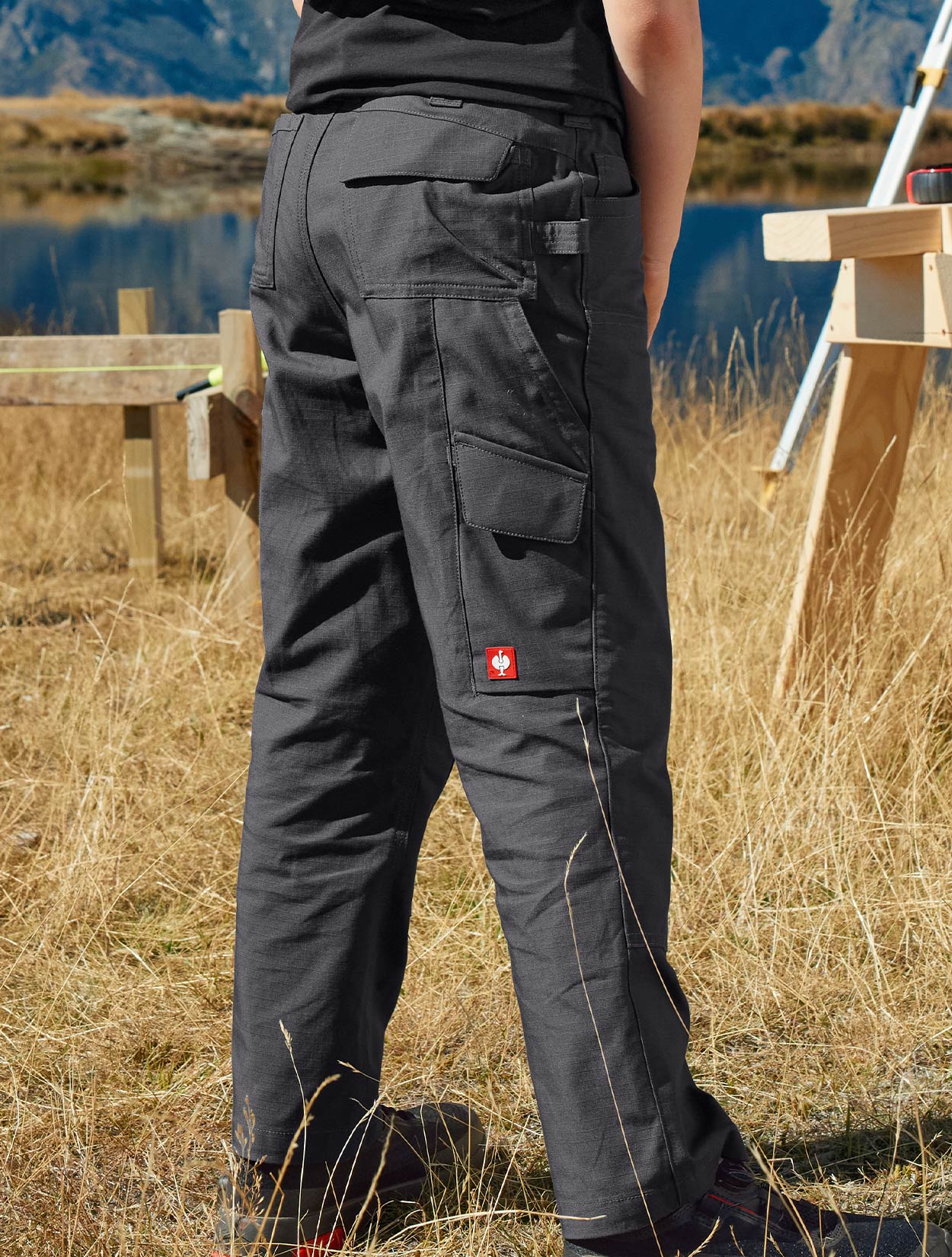 Child wearing dark gray pants with a visible brand logo in an outdoor setting.