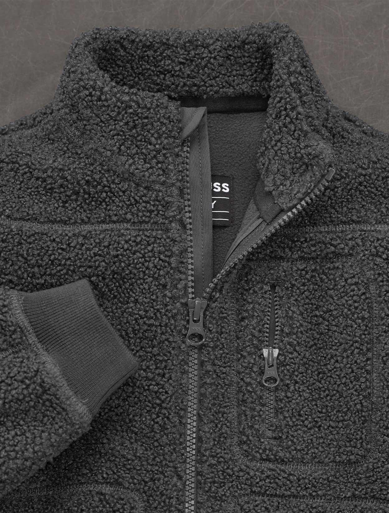 Close-up of a dark gray fleece jacket with a brand logo on a matching background