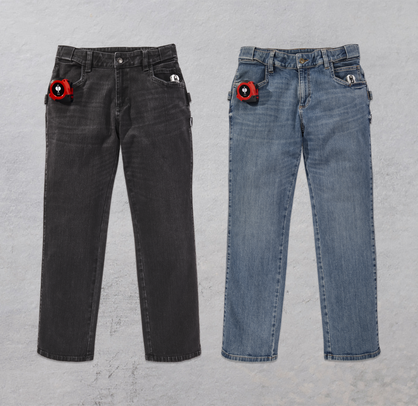 Two pairs of jeans, one black and one blue, are displayed side by side on a light gray surface. Each has a tape measure clipped to the right front pocket.