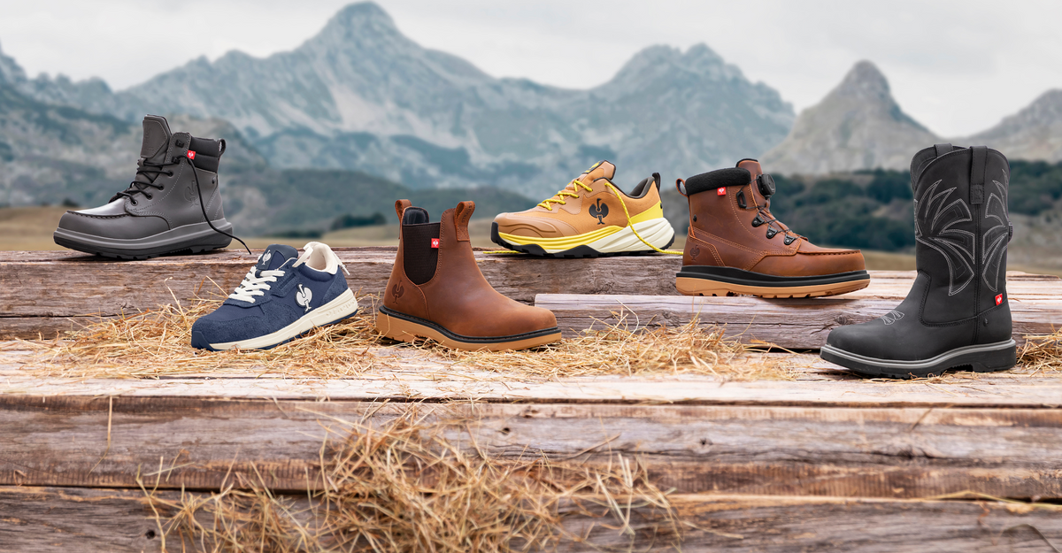 Six pairs of shoes and boots in various styles and colors are displayed on wooden logs with straw, set against a scenic mountain landscape in the background.