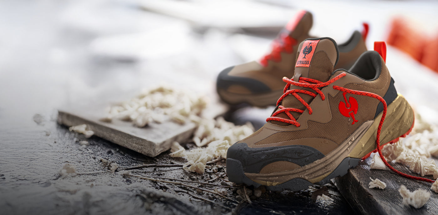 Brown work boots with red laces on a construction site background