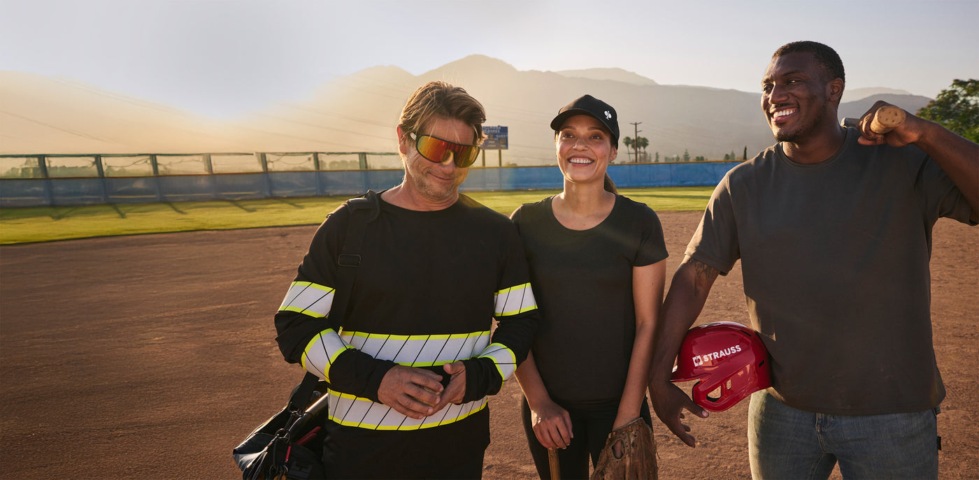 Three people standing on a sports field with mountains in the background