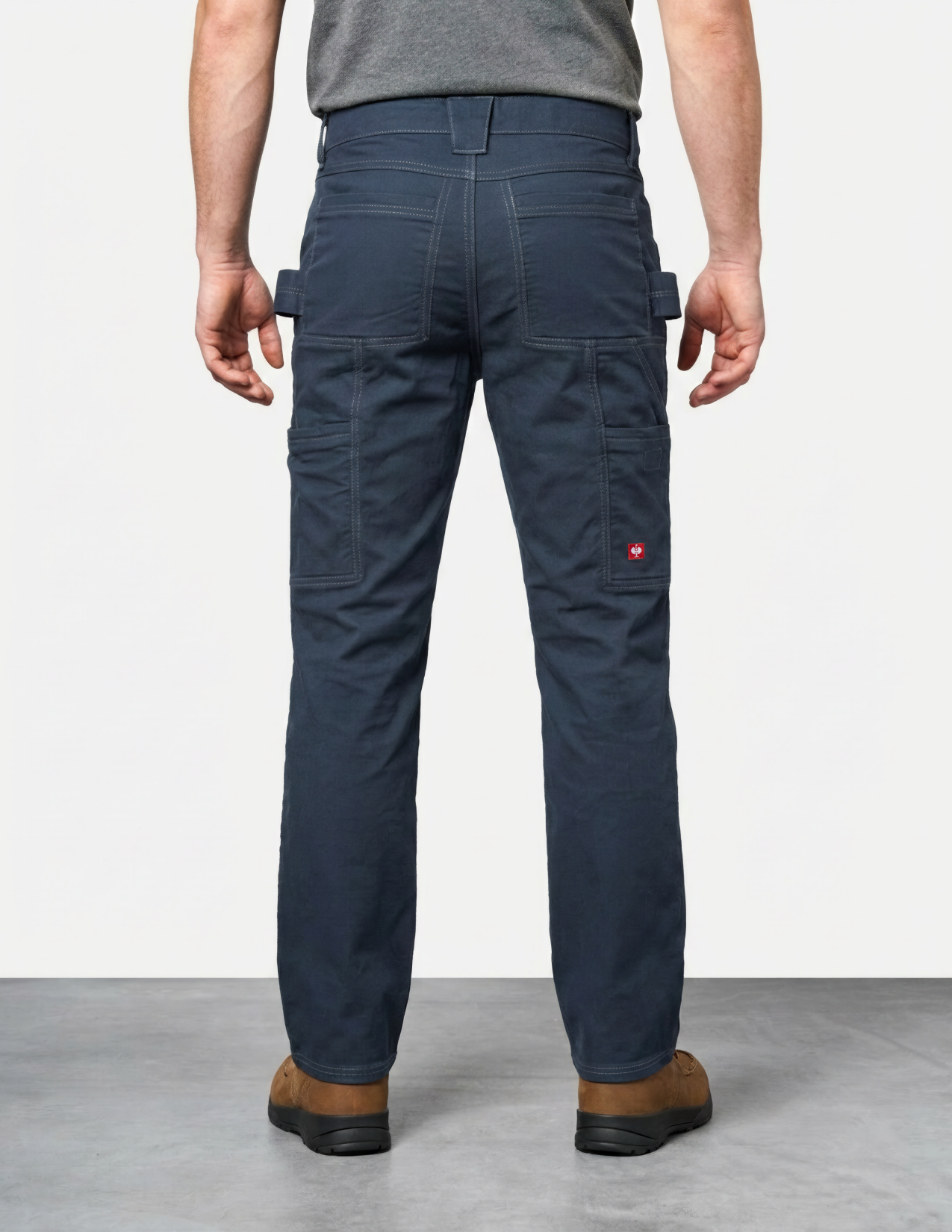 Person wearing navy blue work pants with multiple pockets on a plain background