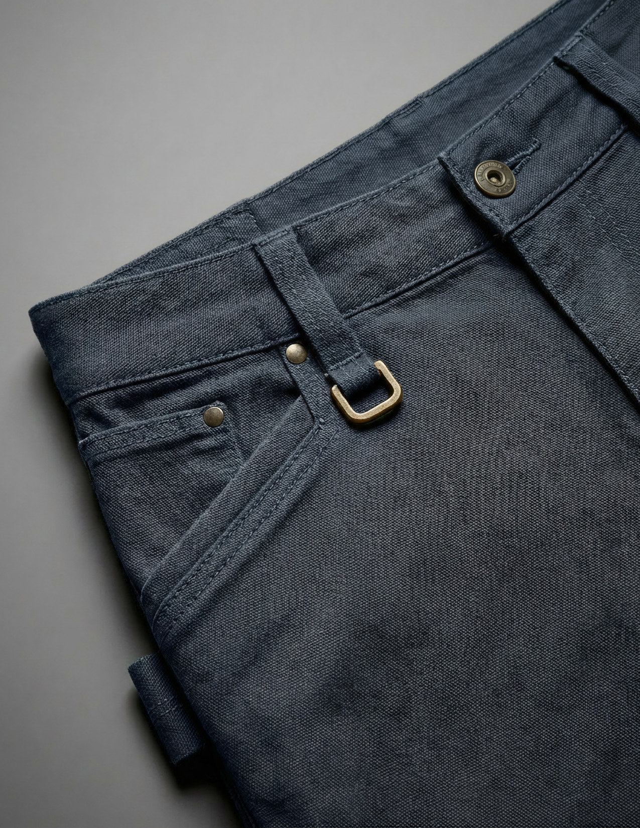 Dark blue pants with a gold buckle on a gray background