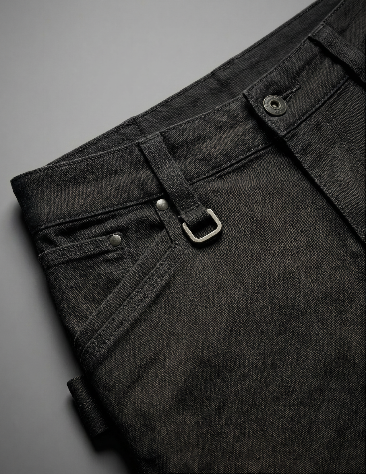 Close-up of black pants with a buckle on a gray background