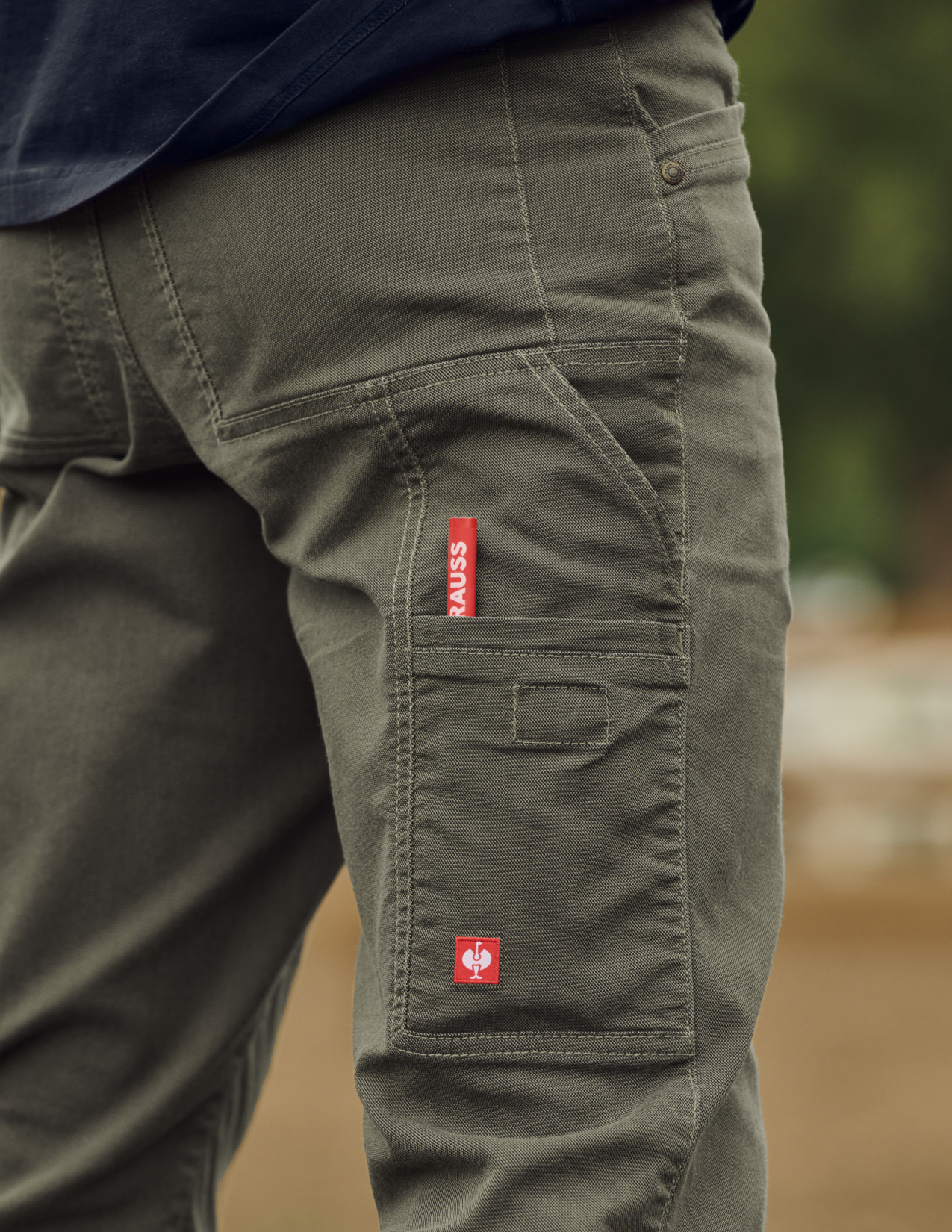 Green cargo pants with a red label on a blurred natural background