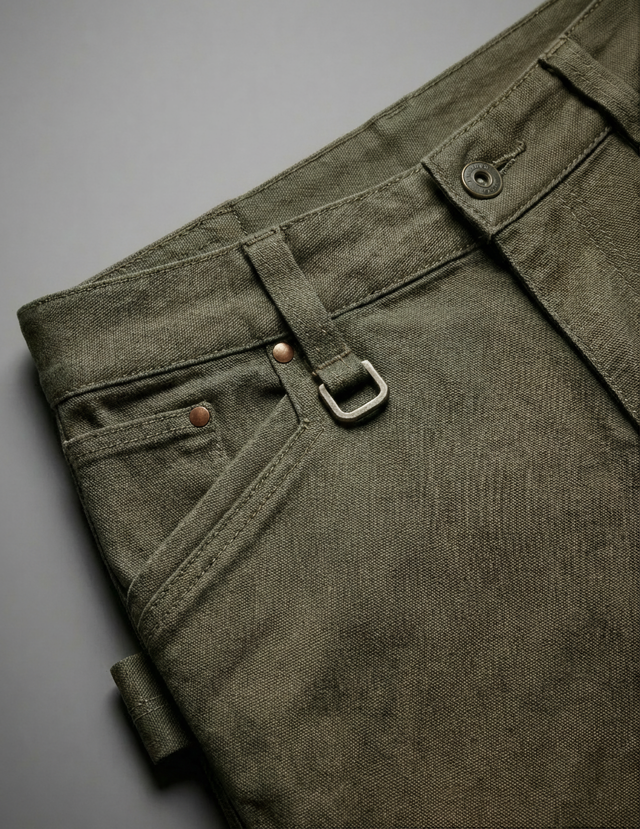 Close-up of green pants with a belt and buckle on a gray background