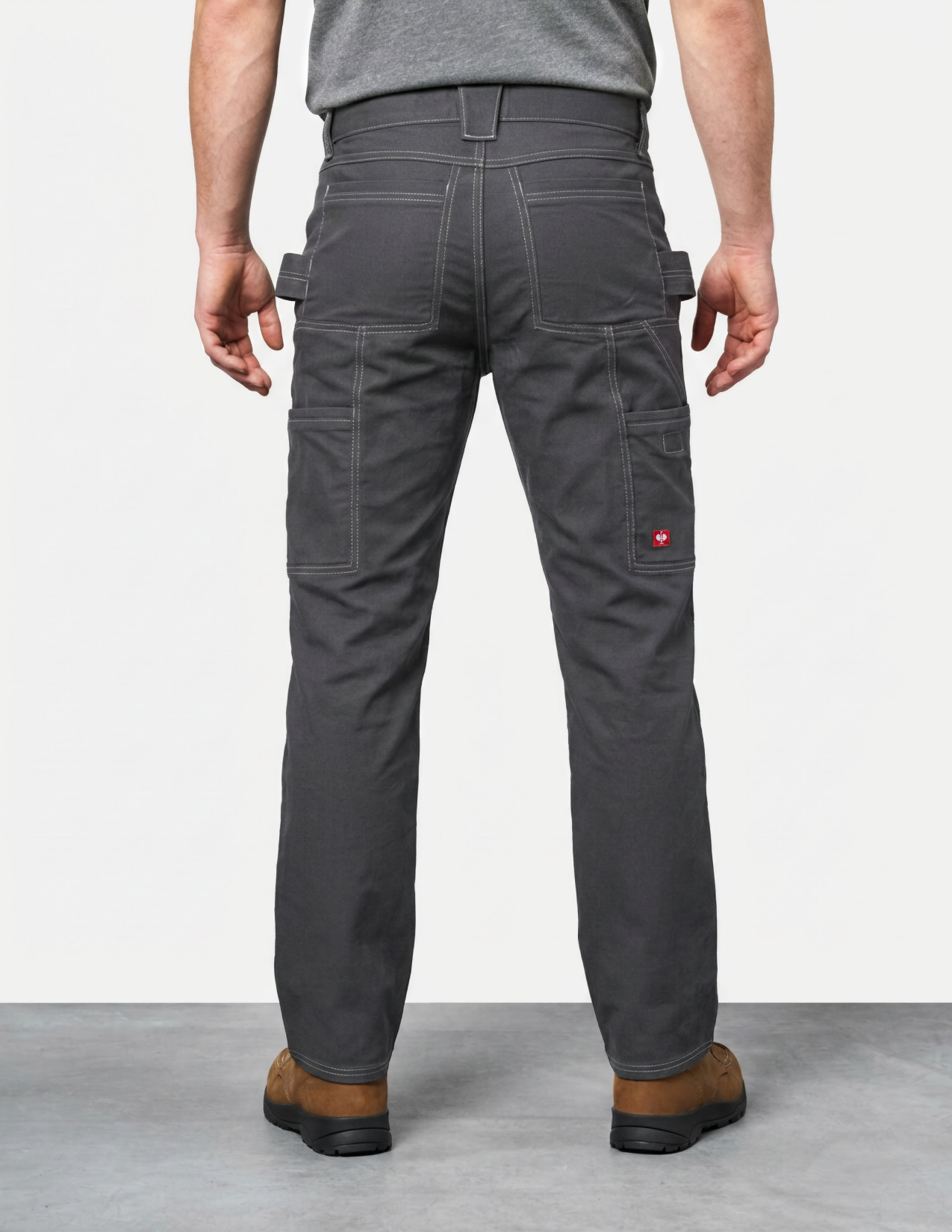 Person wearing gray work pants with multiple pockets on a plain background