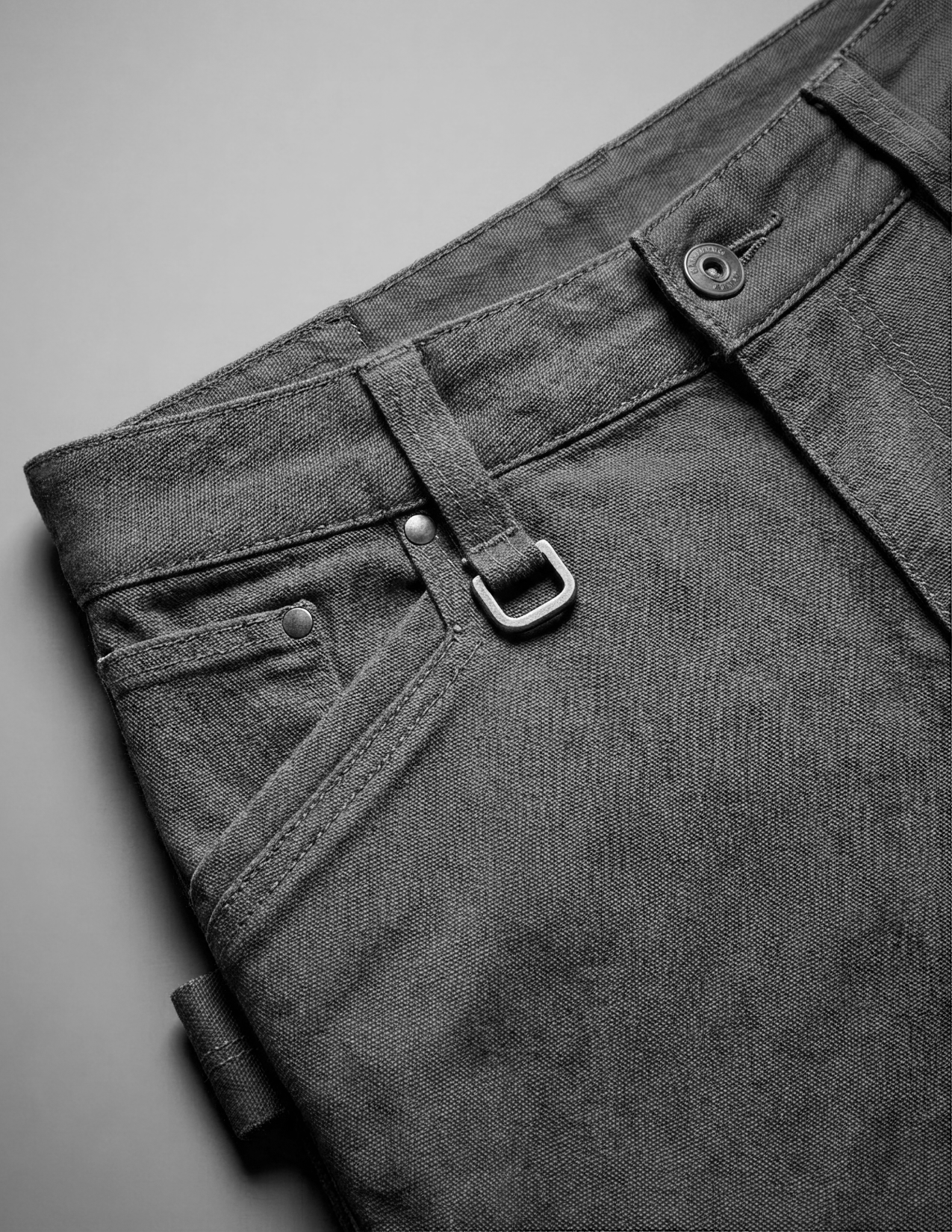 Close-up of dark gray pants with a belt on a gray background