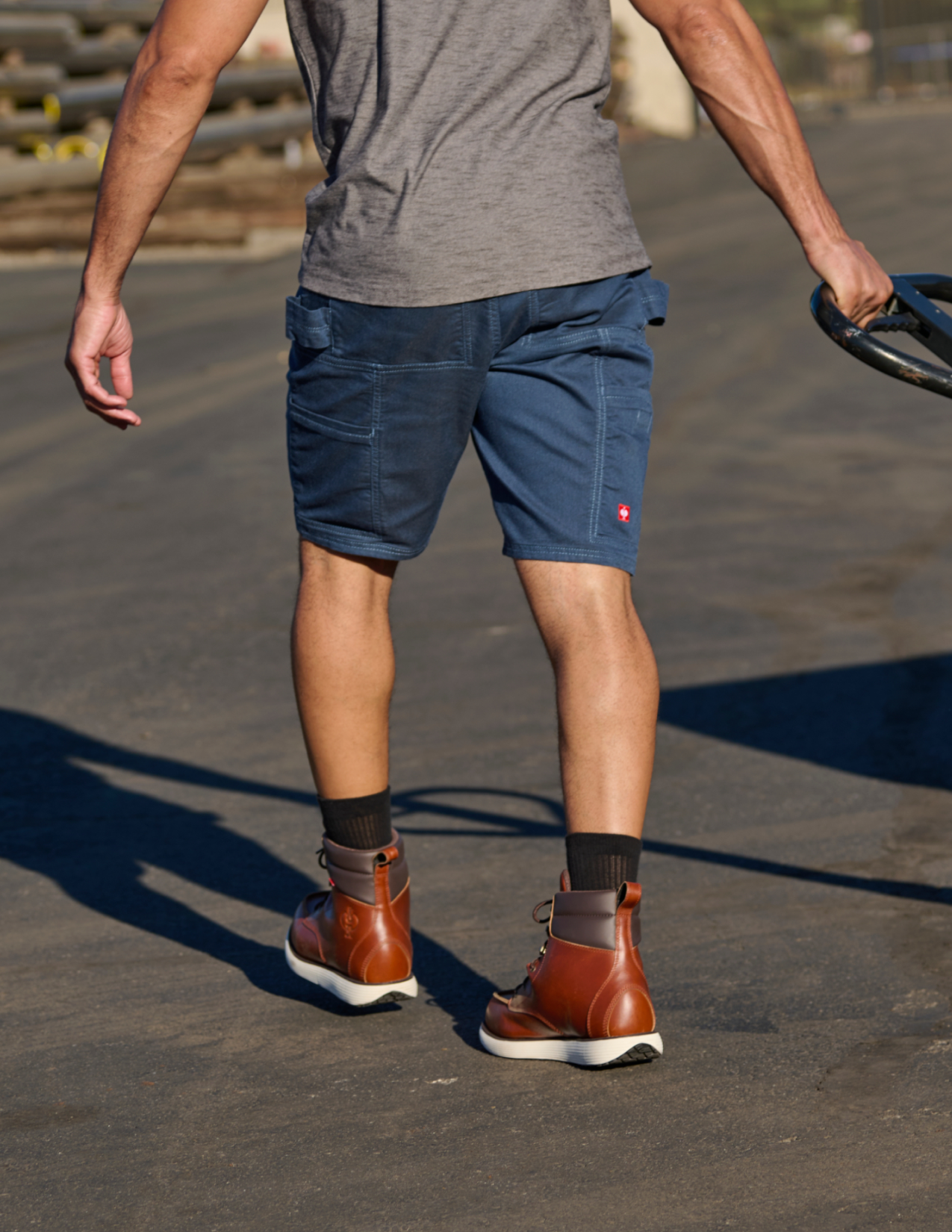 Person wearing blue shorts and brown shoes on a concrete surface