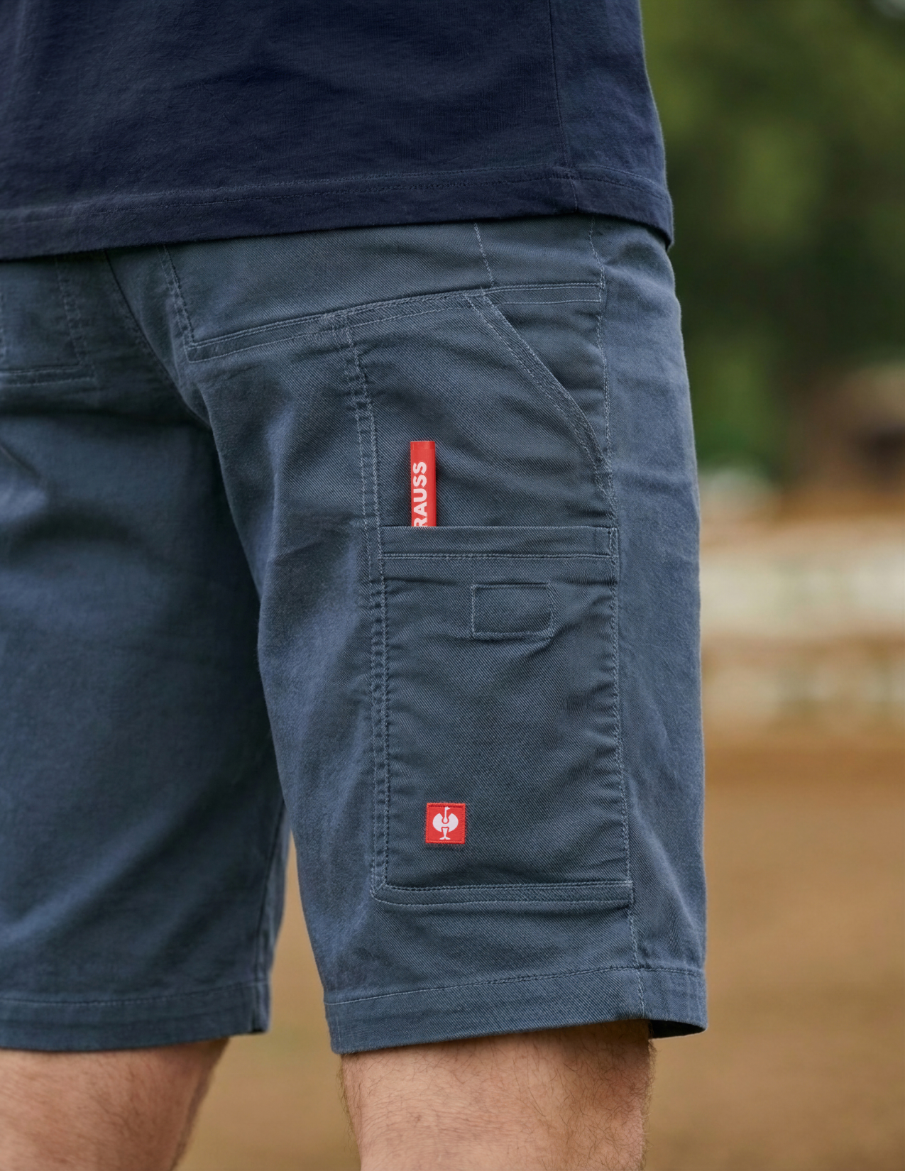 Navy shorts with a red label on a blurred natural background