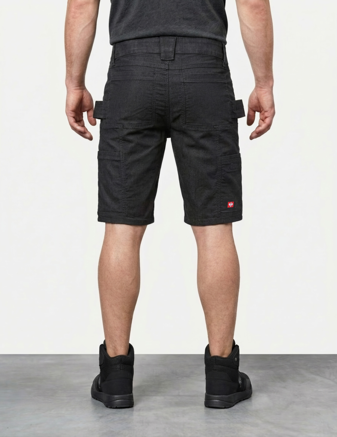 Person wearing black cargo shorts with a visible brand logo on a white background