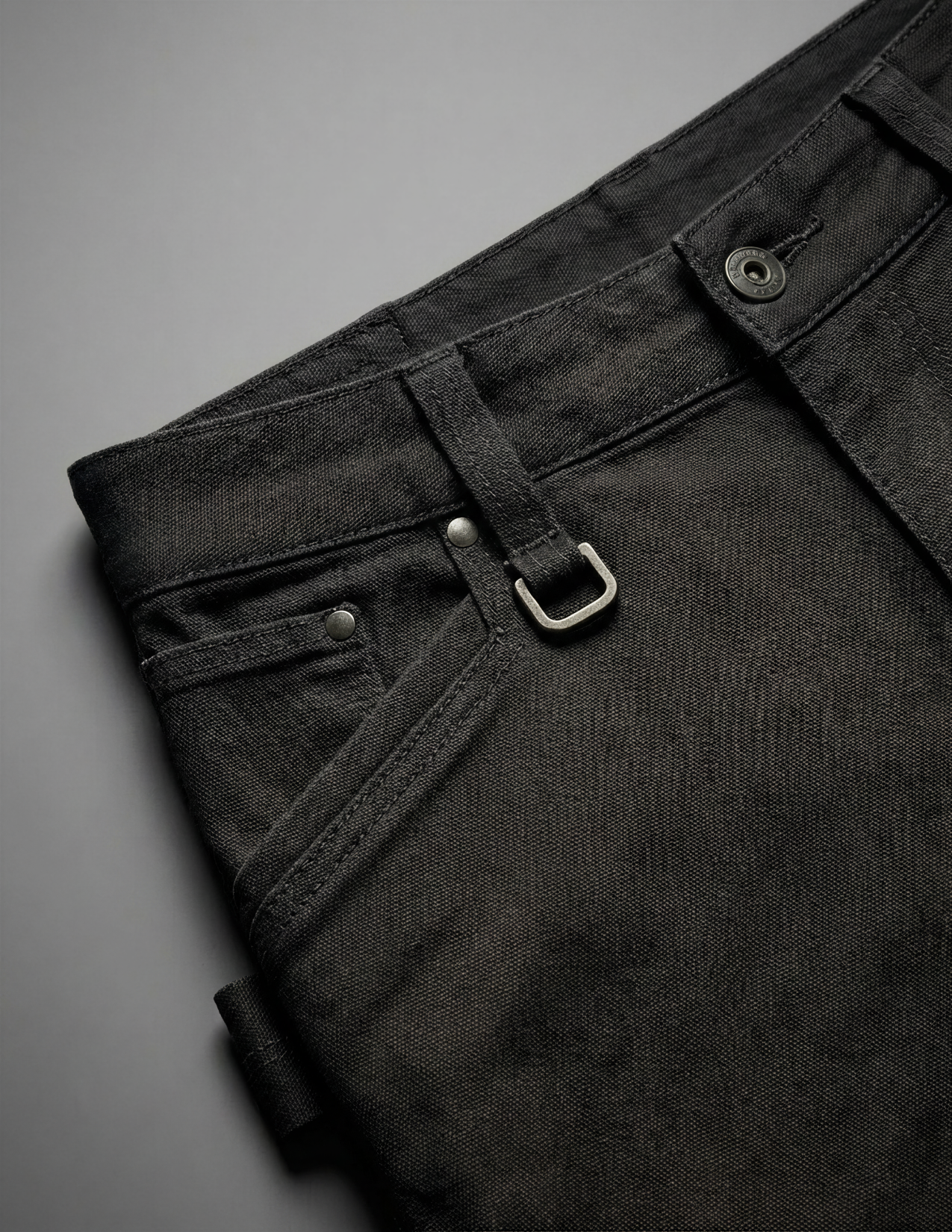 Close-up of black pants with a gray background