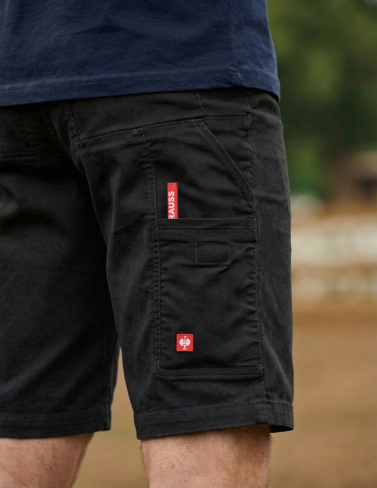 Black shorts with red labels on a blurred natural background
