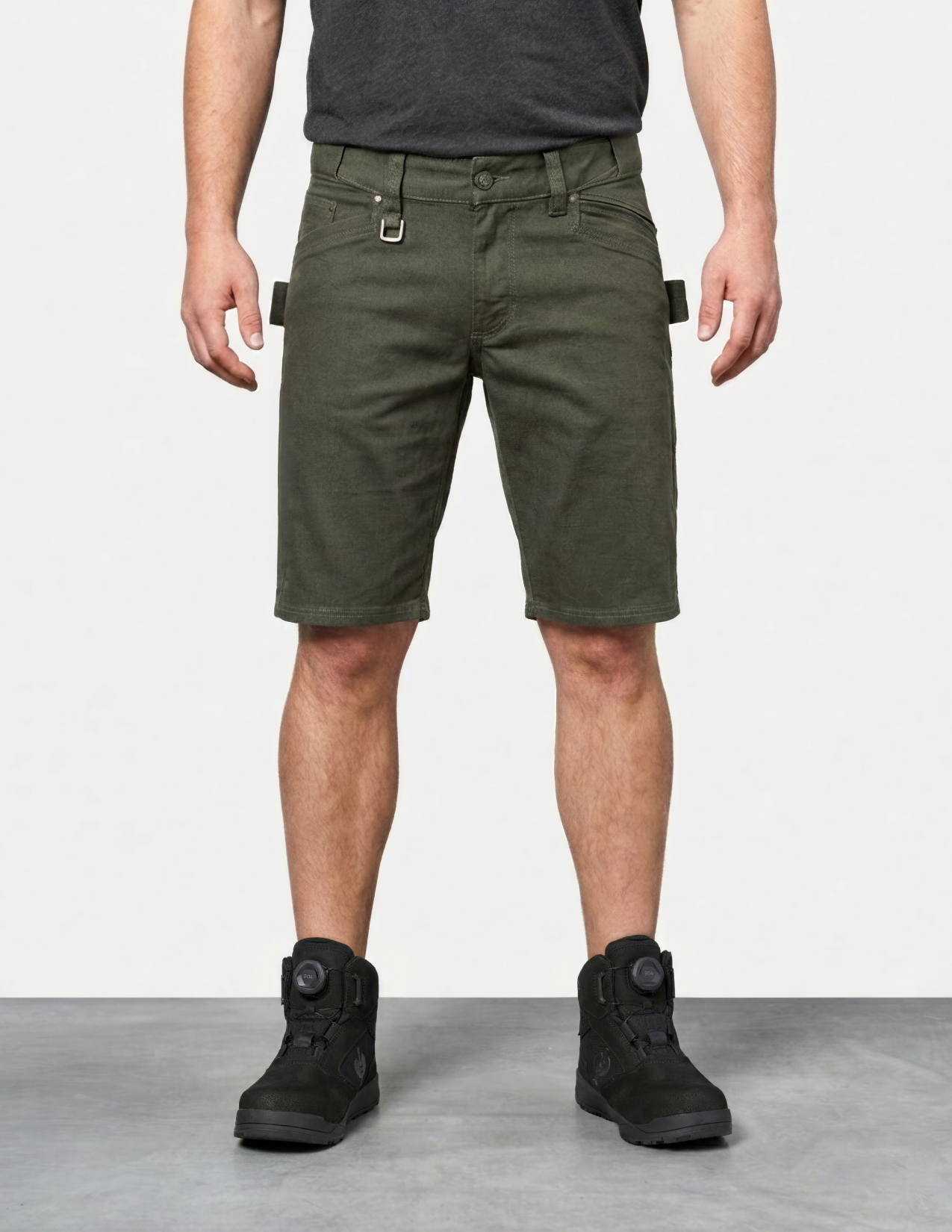 Person wearing green shorts and black boots on a plain background