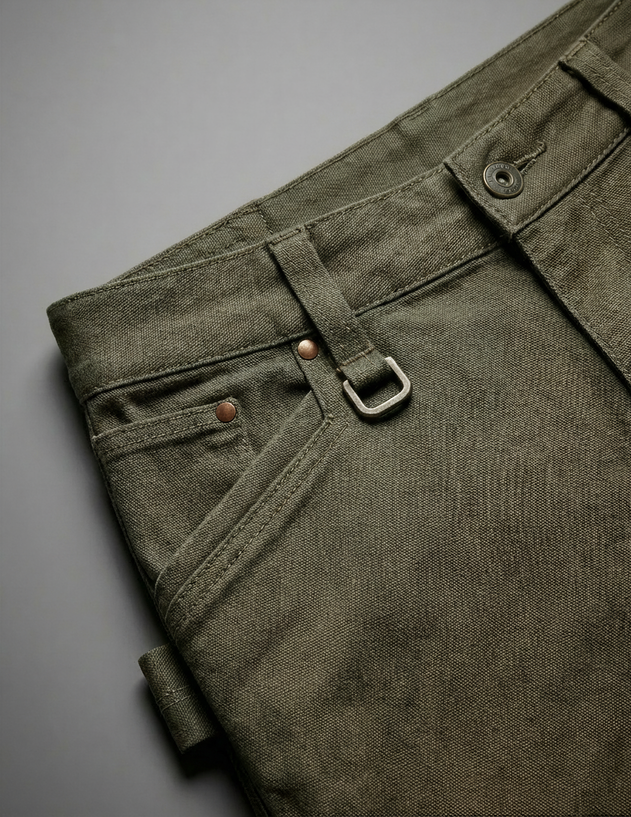 Close-up of olive green pants with a buckle on a gray background