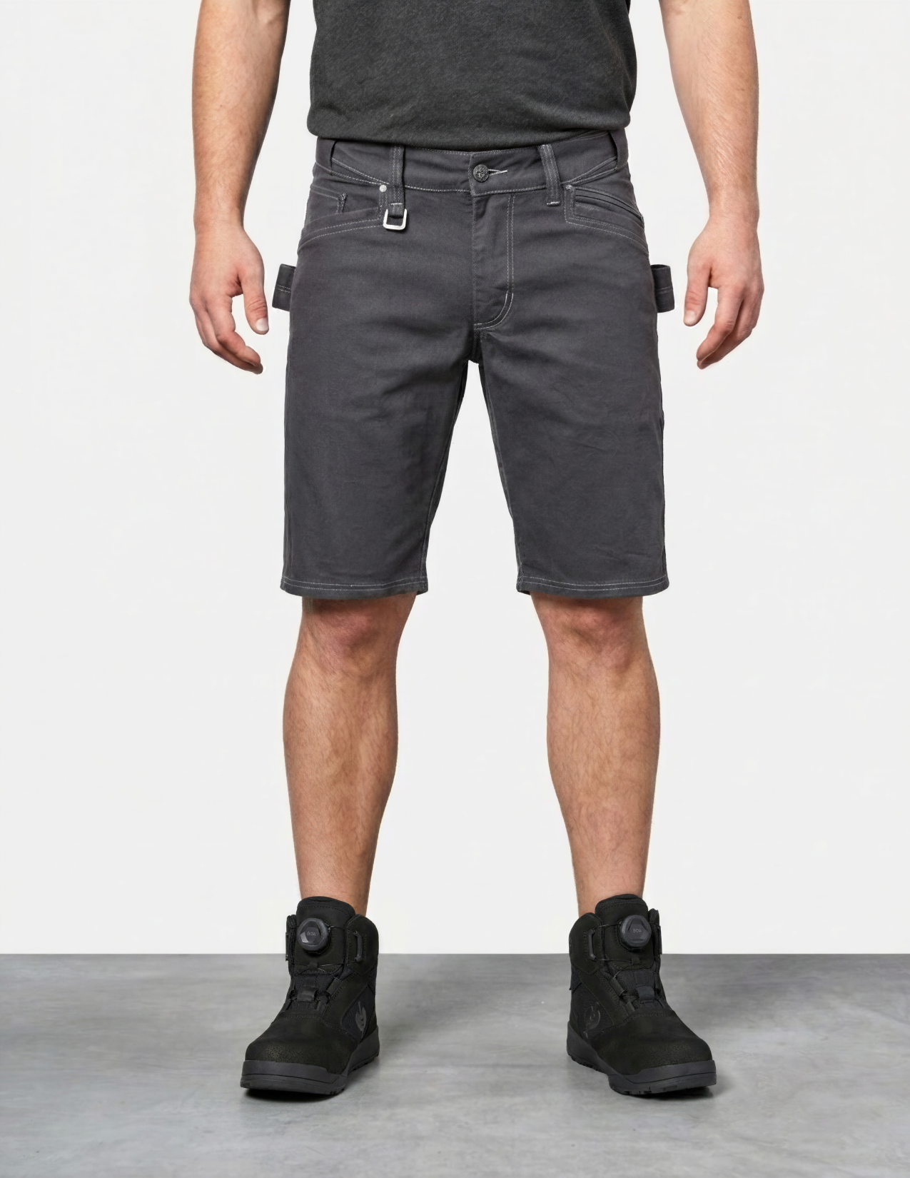 Person wearing gray cargo shorts and black boots on a plain background