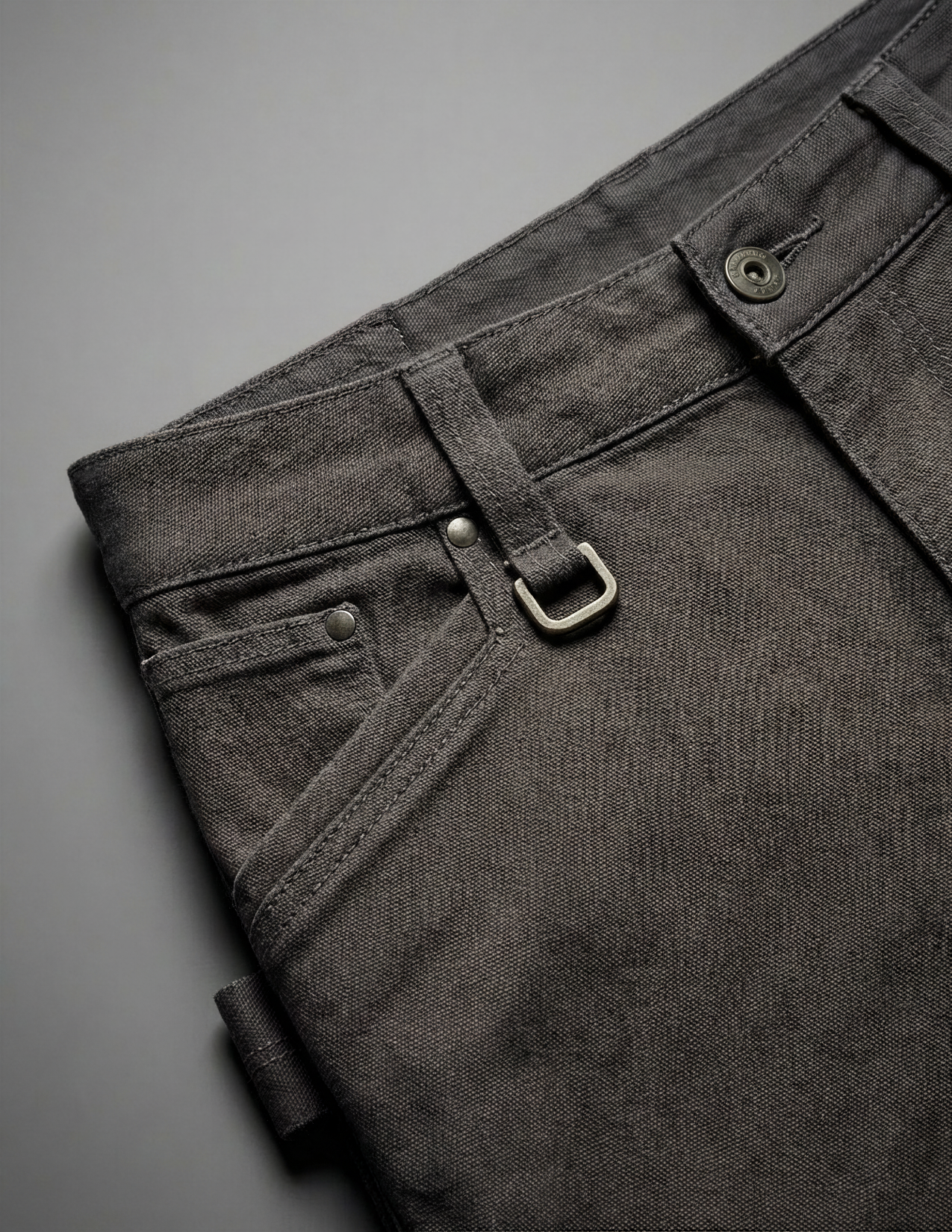 Close-up of grey pants with metal buttons on a gray background