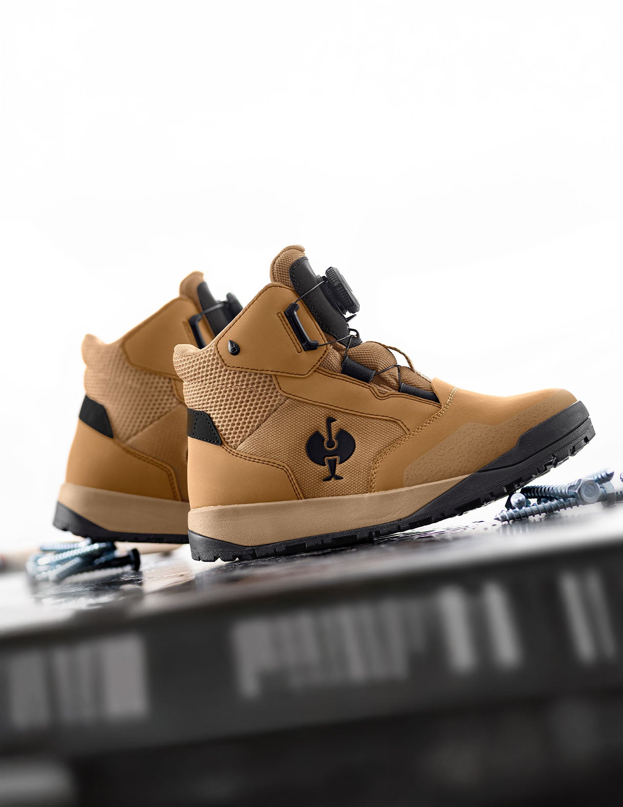 Pair of brown and black boots on a reflective surface with a blurred background