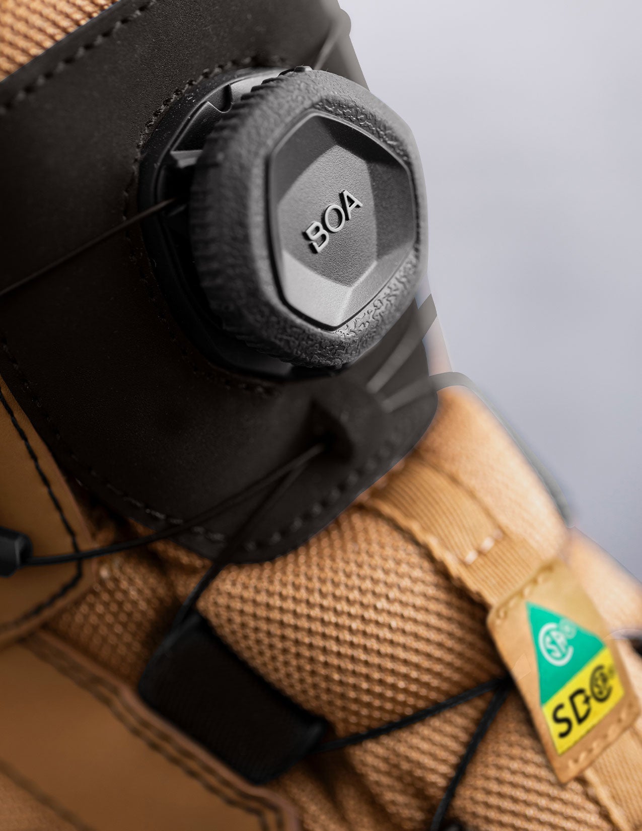 Close-up of a brown boot with BOA system buckle on a gray background
