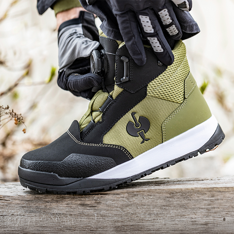 Green and black hiking boot with a blurred natural background