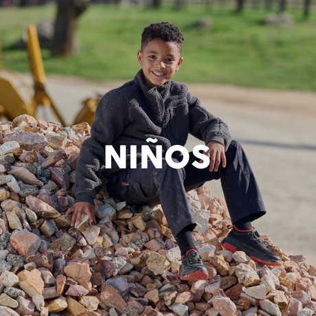 Child sitting on rocks with 'NIñOS' text overlay