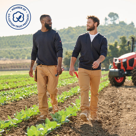 Two farm workers walk in a field in Strauss workwear made with US Cotton