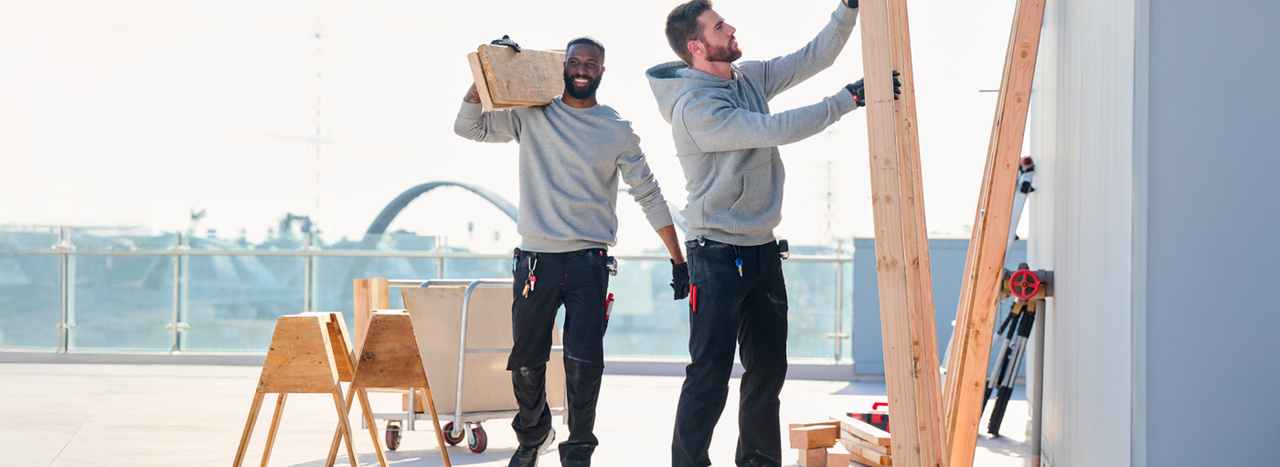 Two men working on a construction project with tools and materials in an outdoor setting.