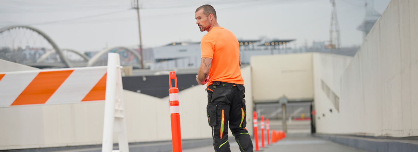 Man in hi vis orange shirt looks back over his shoulder