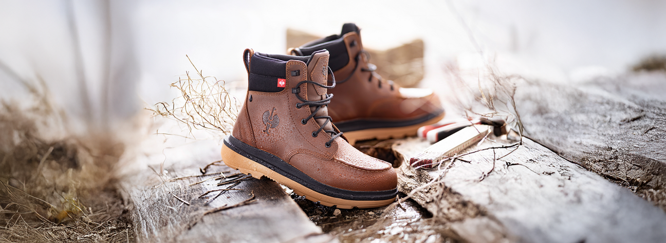 Pair of brown leather boots with black soles on a wooden surface.