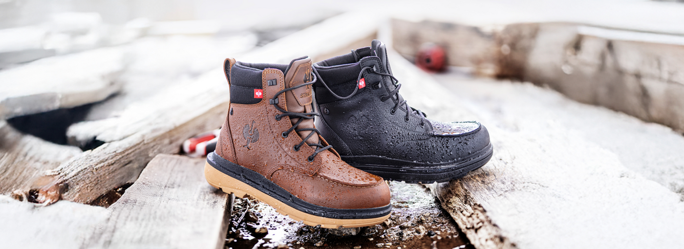 Pair of brown and black boots on a wooden surface with snow in the background