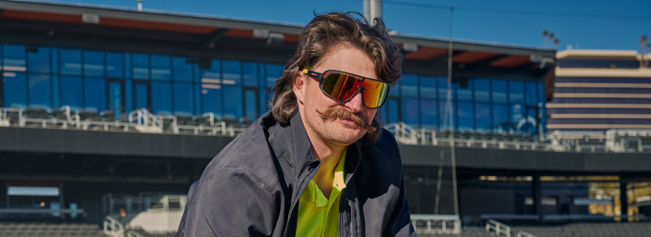 Man wearing reflective sport sunglasses with colorful mirrored lenses outdoors.