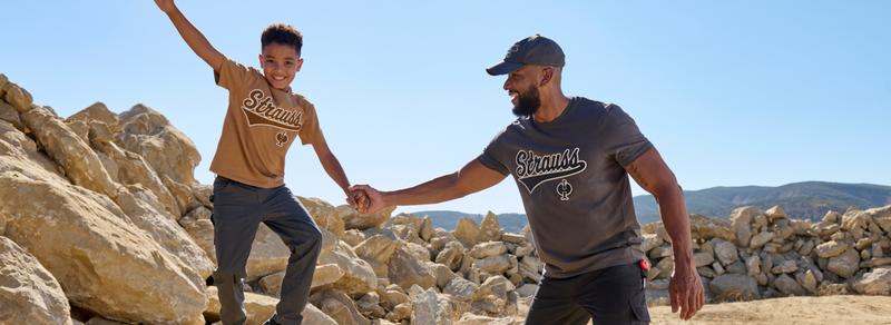 Two people holding hands on a rocky landscape with mountains in the background