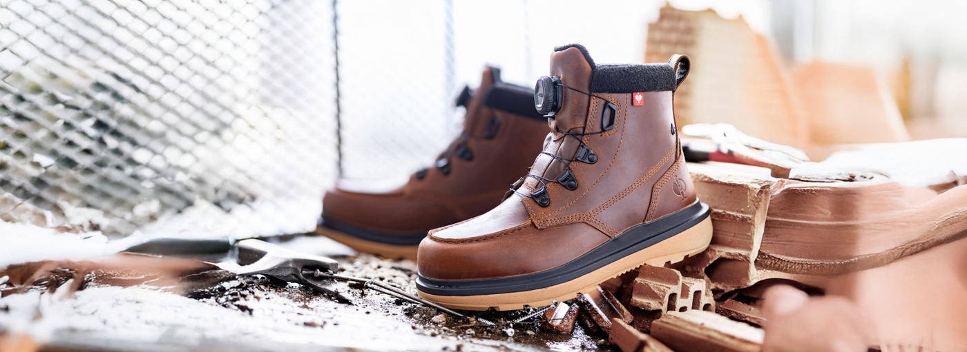 Brown leather safety toe work boots with laces on construction site.