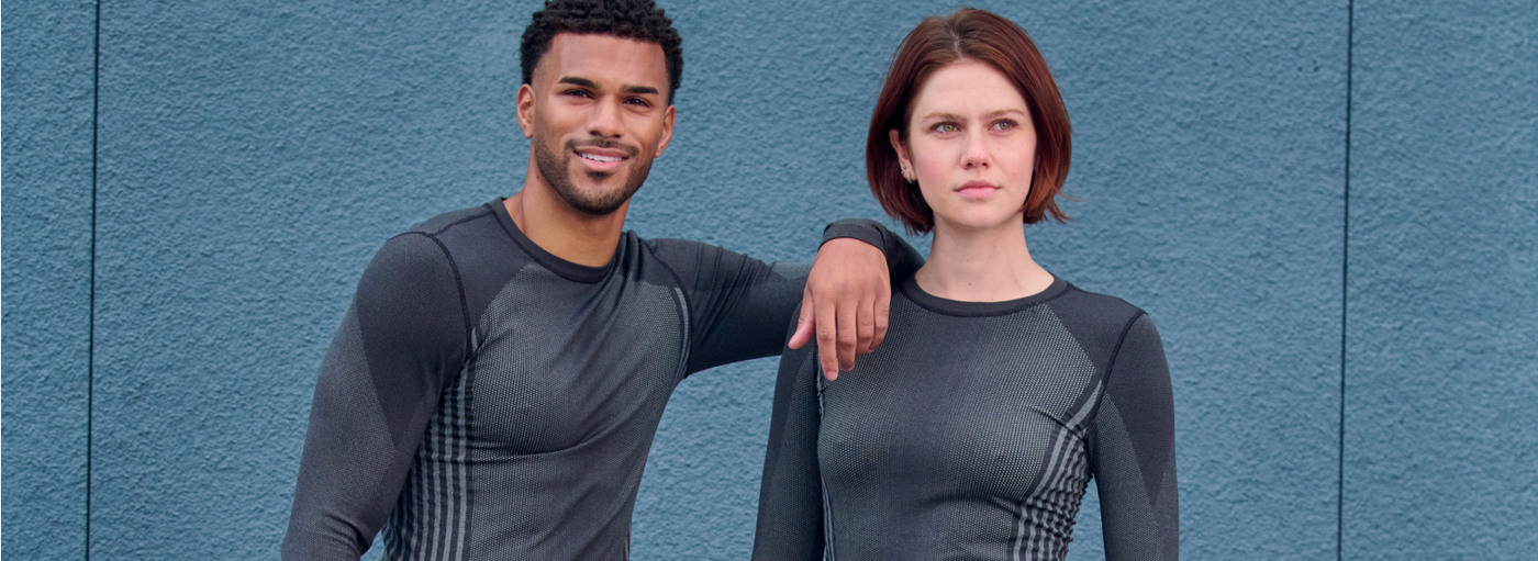 Two people wearing matching gray athletic outfits against a blue background