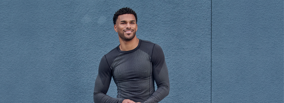 Man wearing a gray long-sleeve shirt against a blue background