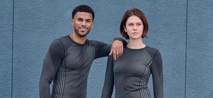 Two people wearing matching gray athletic outfits against a blue background
