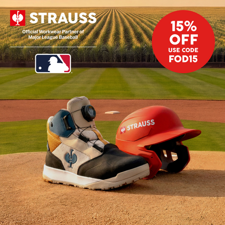 A safety boot in white, black, and blue with a BOA dial closure, shown next to a red Strauss batting helmet on a baseball field dirt mound. A red promotional sticker in the top right corner reads '15% OFF USE CODE FOD15'.