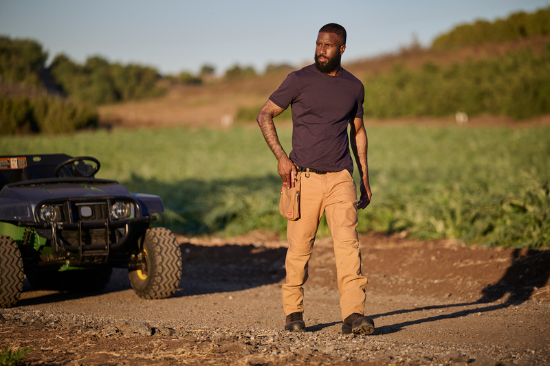 Man standing in a field with an ATV in the background