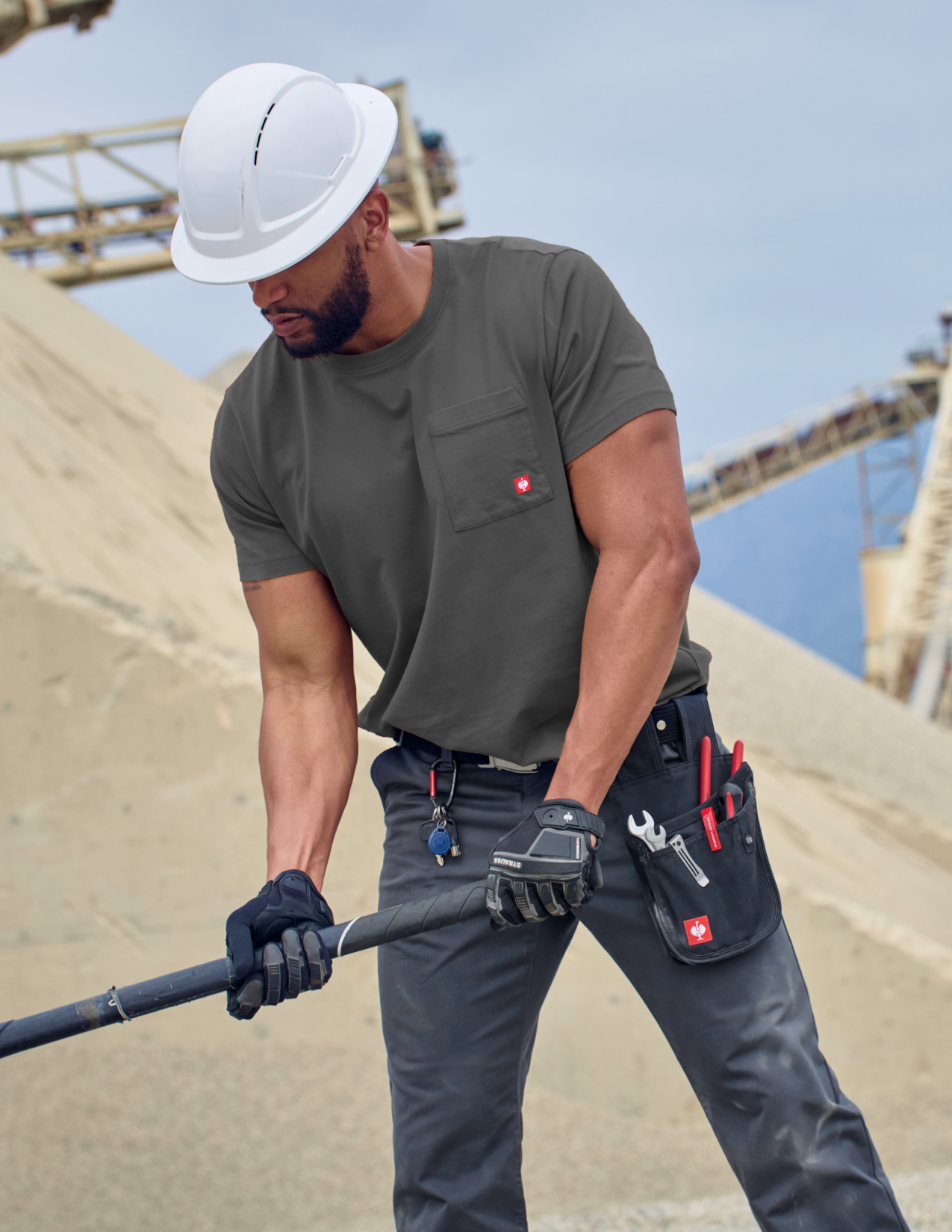 Man in a dark grey shirt with tools on a construction site