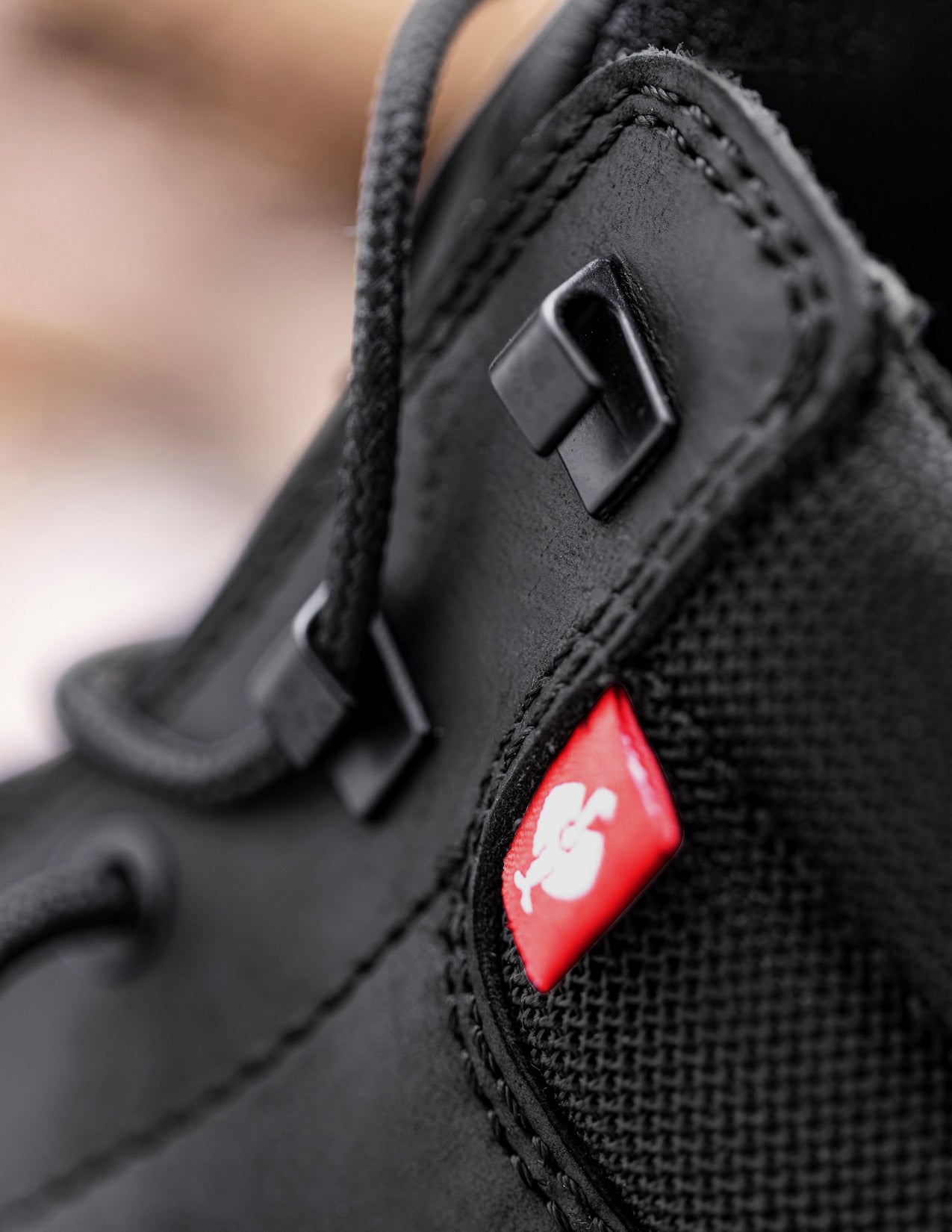 Close-up of a black shoe with a red label featuring a white logo.