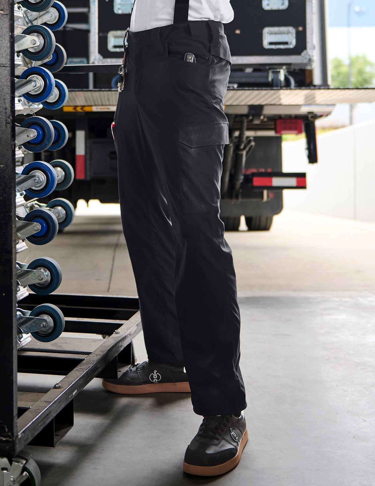 Person wearing black pants and shoes in a workshop setting with tools and equipment.