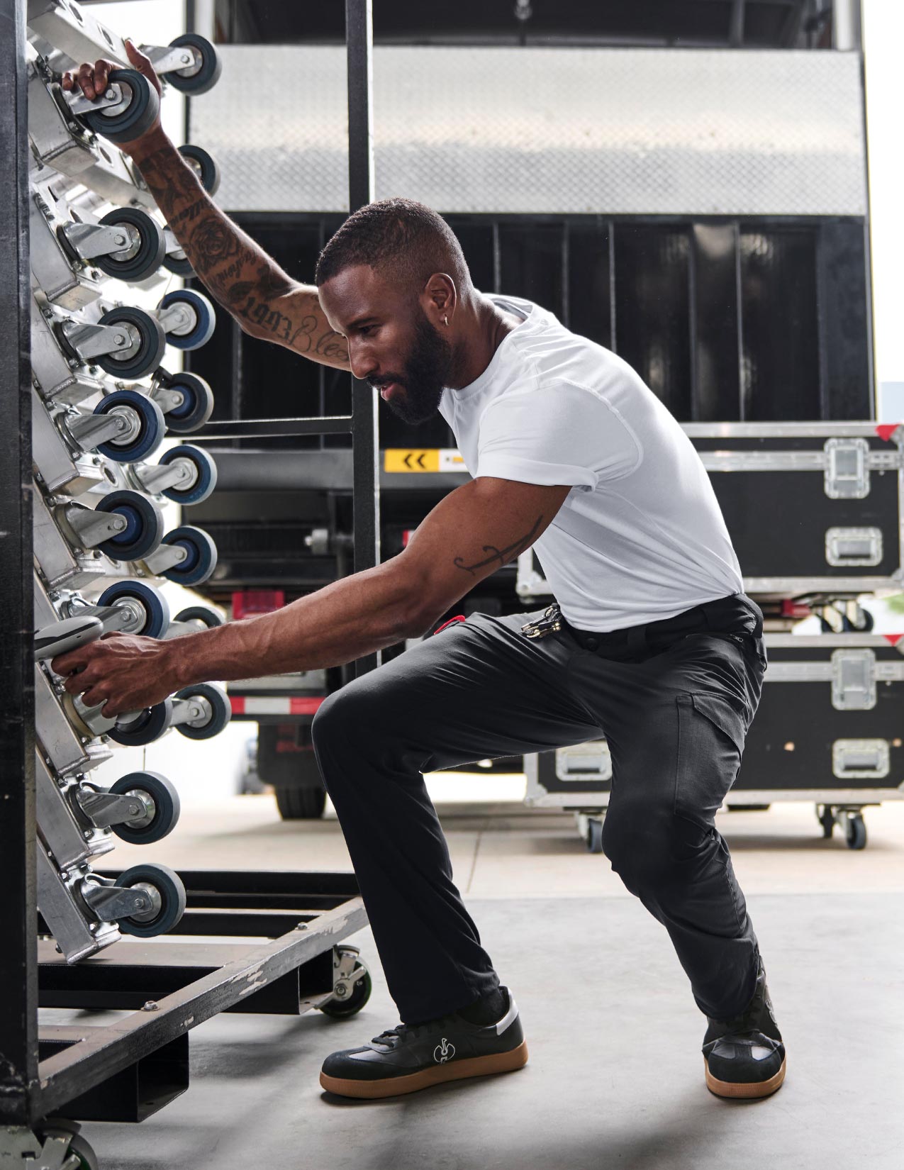 A man is squatting down with a vehicle in the background