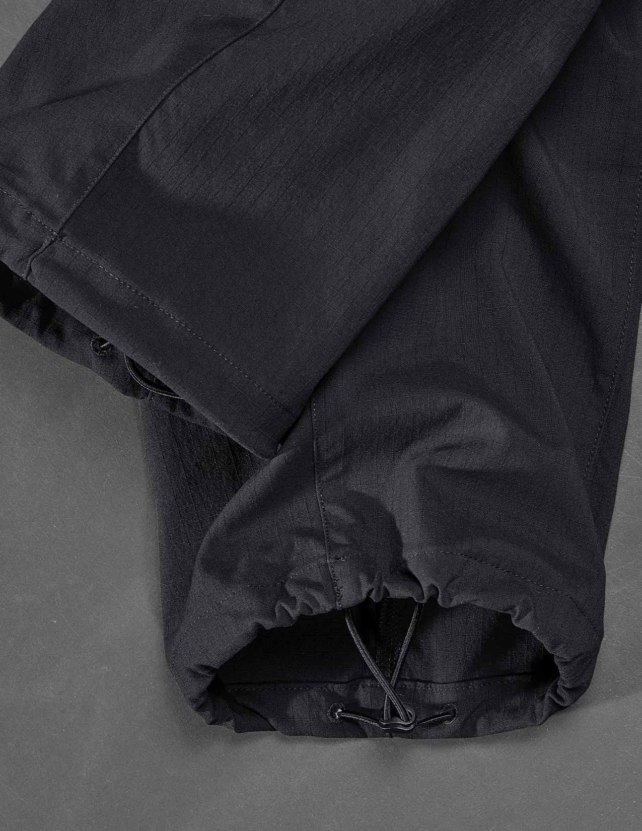 Black trousers with a drawstring on a gray background