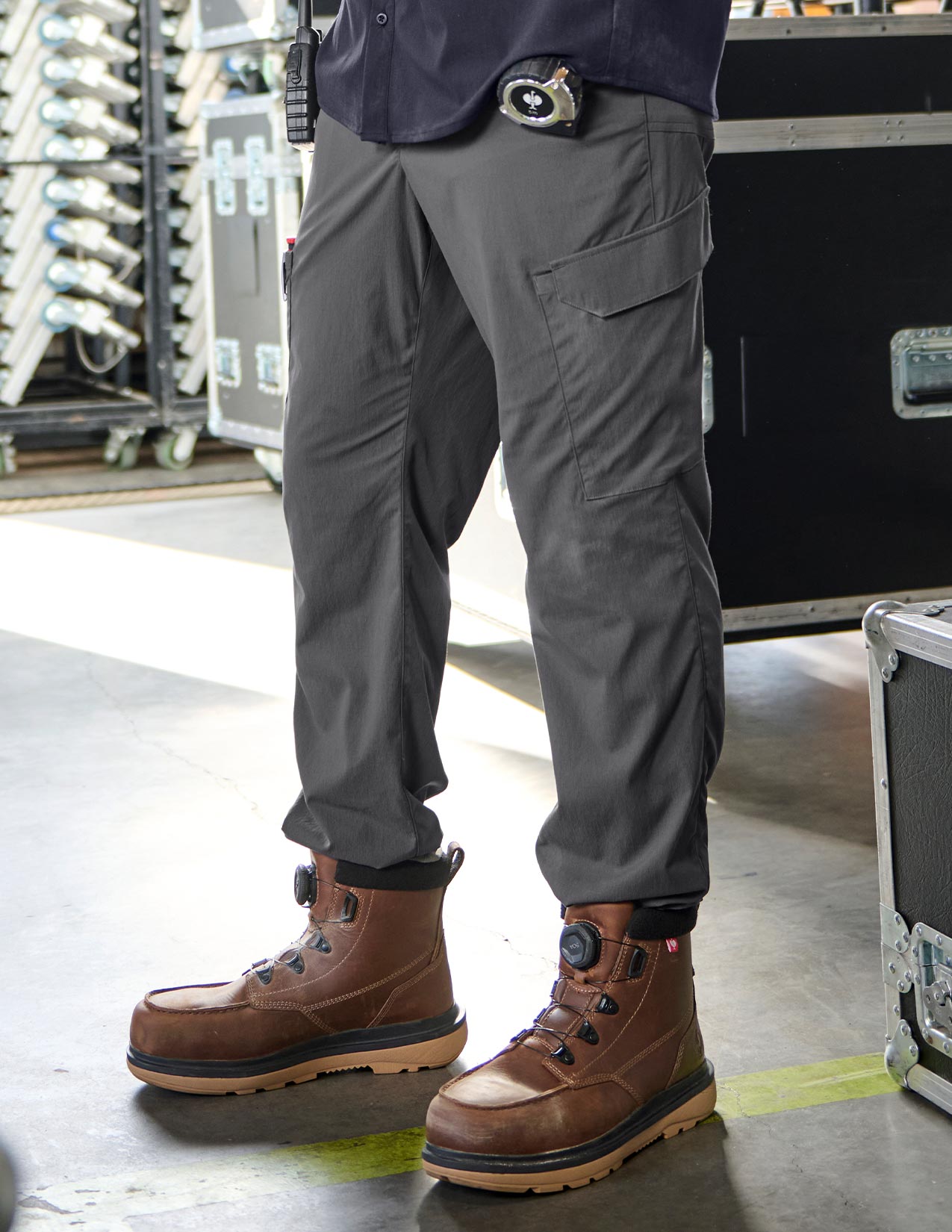 Person wearing gray pants and brown boots in a warehouse setting