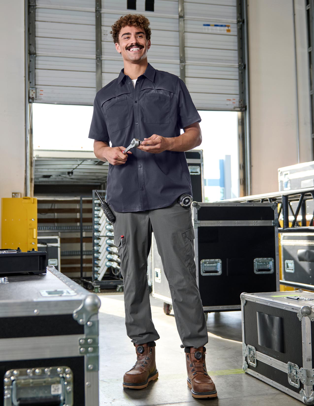 Man in work attire standing in a warehouse with equipment around