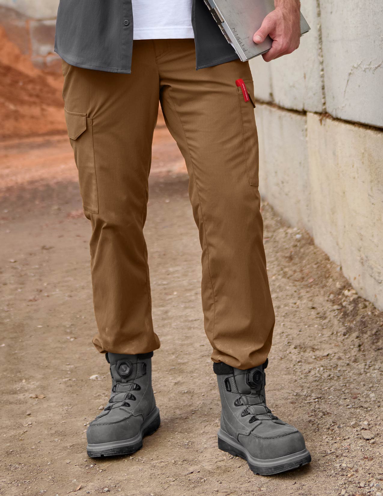 Person wearing brown pants and gray boots standing on a dirt surface.
