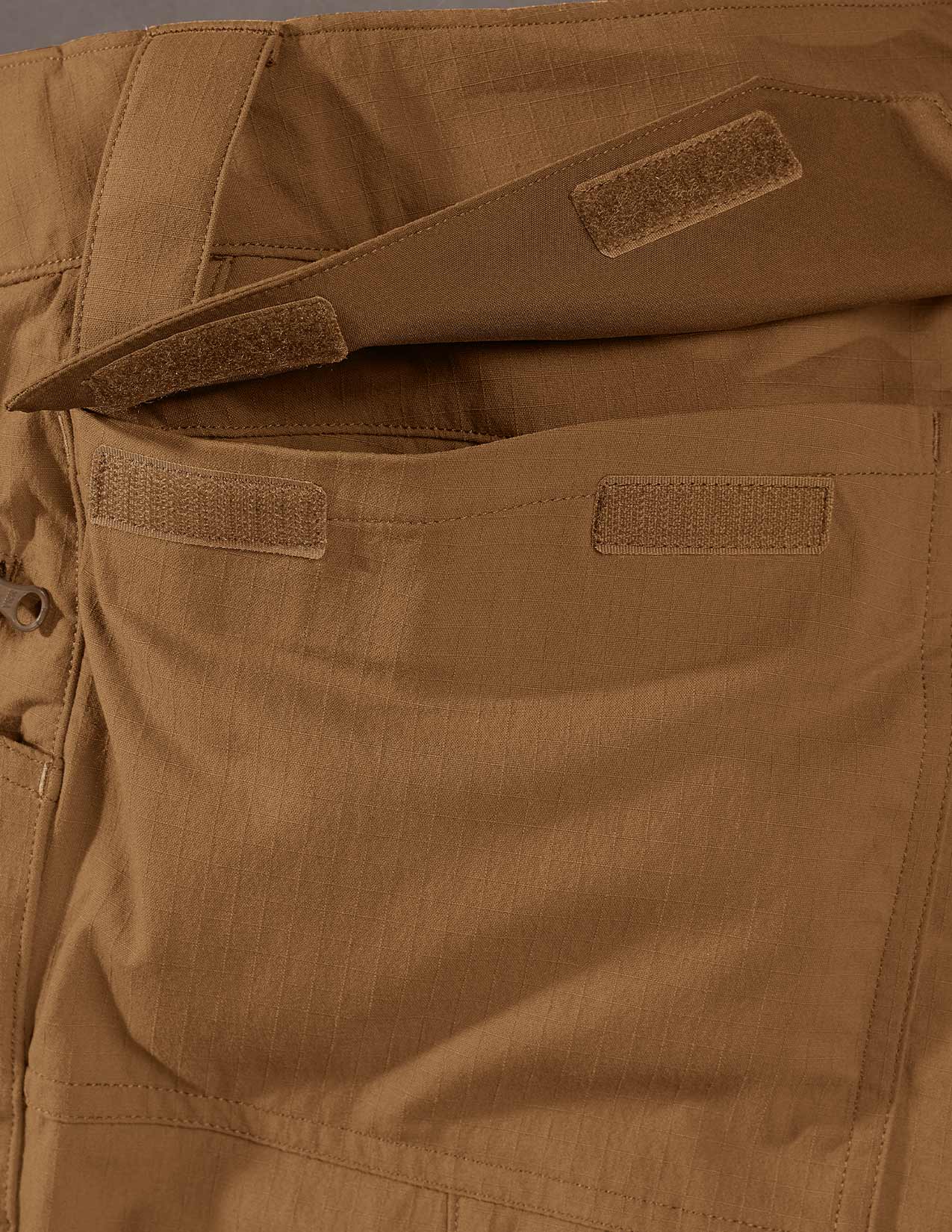 Close-up of brown tactical pants with multiple patches.