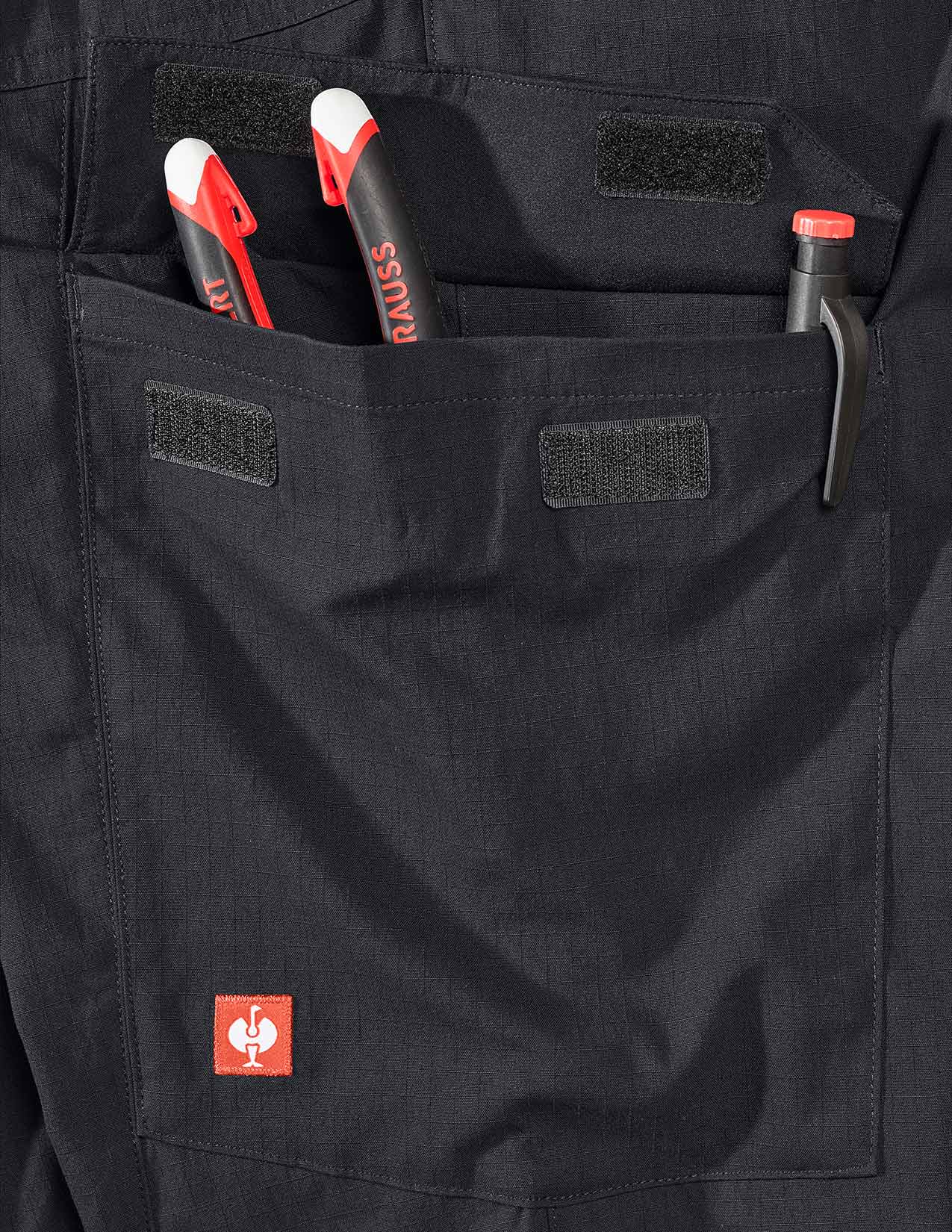 Black pants with a pocket containing tools and a visible brand logo.