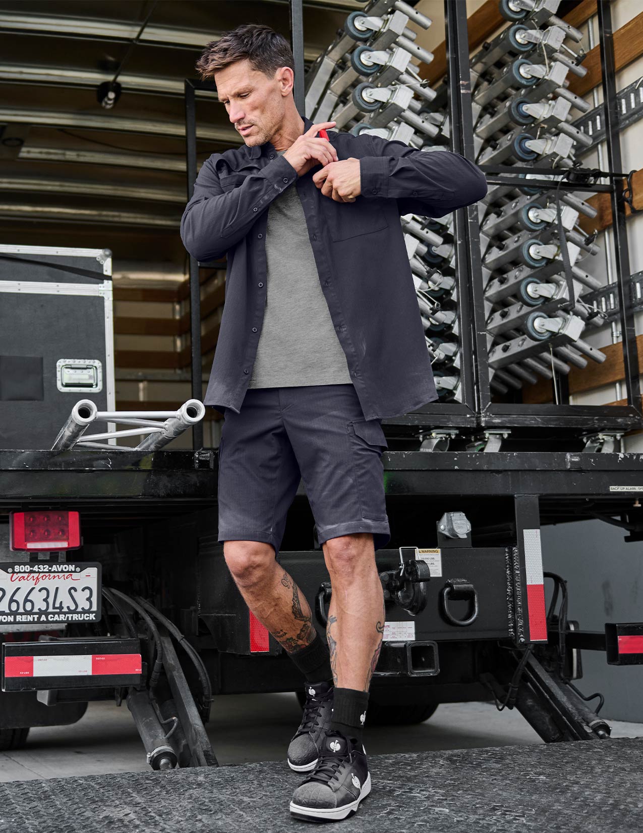 Man adjusting his jacket in front of a truck with equipment